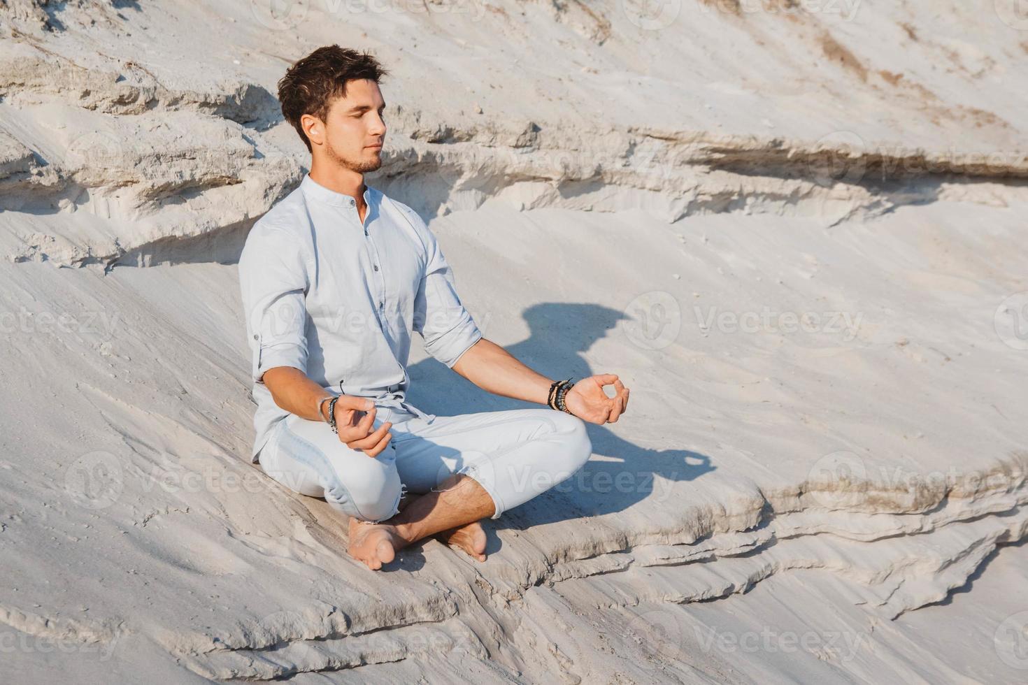 man zit in meditatiehouding op zandstrand foto