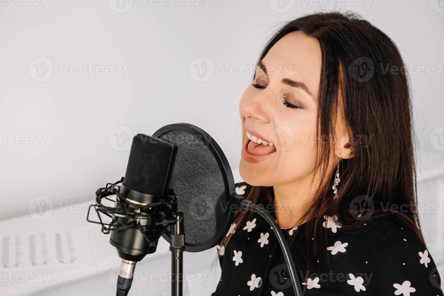 portret van mooie vrouw zingt een lied in de buurt van een microfoon in een opnamestudio. plaats voor tekst of reclame foto