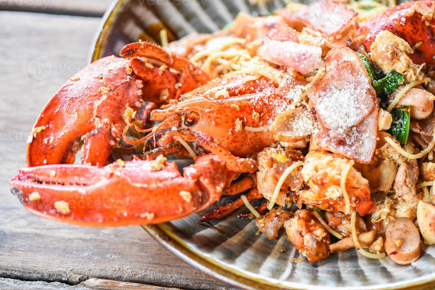 gegrilde kreeft worst ham groenten en kaas spaghetti zeevruchten op houten tafel - schaaldieren zeevruchten plaat met kreeft diner eten gekookt foto