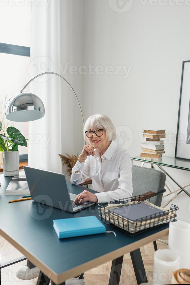 moe senior mooie grijze haren vrouw in witte blouse lezen van documenten op kantoor. werk, senioren, problemen, een oplossing vinden, ervaringsconcept foto