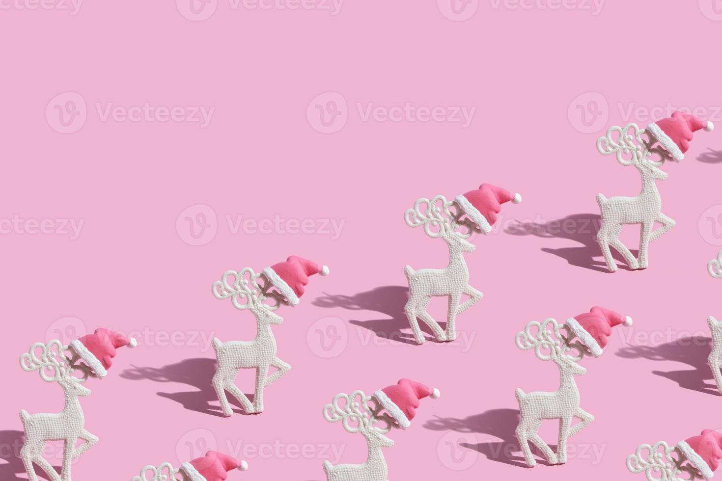 patroon met glamoureuze rendieren in een kerstmuts op een roze achtergrond foto