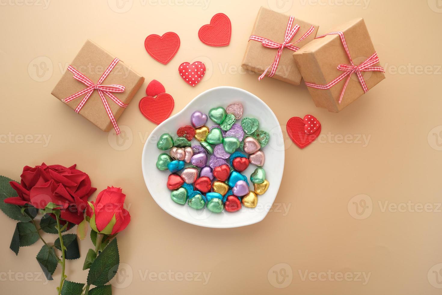 snoep in een hartvormig bord, cadeau, rozenbloem op tafel foto