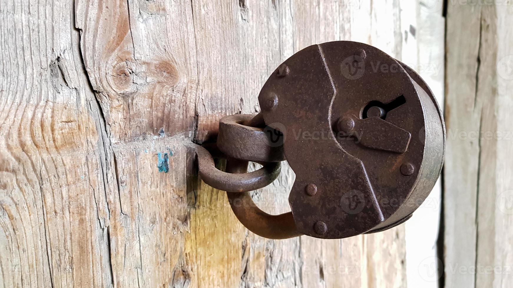 oud vintage metalen hangslot op een gesloten houten deur van een oude boerderij. de ware stijl van het dorp. detailopname. focus op het kasteel. houten achtergrond, textuur. kopieer ruimte foto