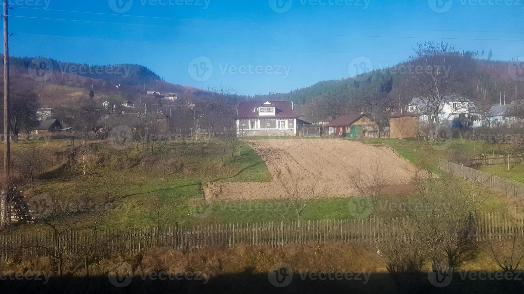 landschapsmening van een bergdorp in de Karpaten in de herfst vanuit het treinraam. een uitzicht vanuit een oude trein van een bergdorp foto