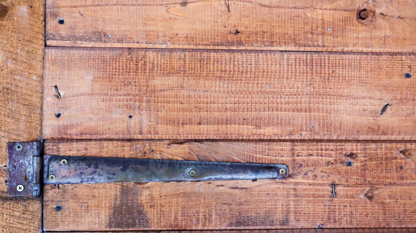 oude houten achtergrond met een roestige scharnier. antieke deurscharnieren. zwart metaal op bruin hout close-up gedetailleerde weergave. vintage deur scharnier close-up deur achtergrond. foto