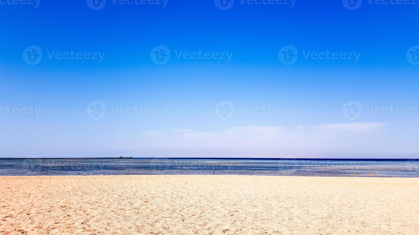 een prachtig zandstrand zonder mensen en een tropische blauwe zee met blauwe hemelachtergrond. foto