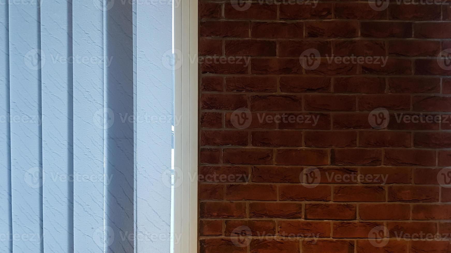 groot raam met verticale witte of grijze jaloezieën, loft, bakstenen muur, industrieel interieur. zonlicht uit een raam op bakstenen muren in een kamer of kantoor. foto