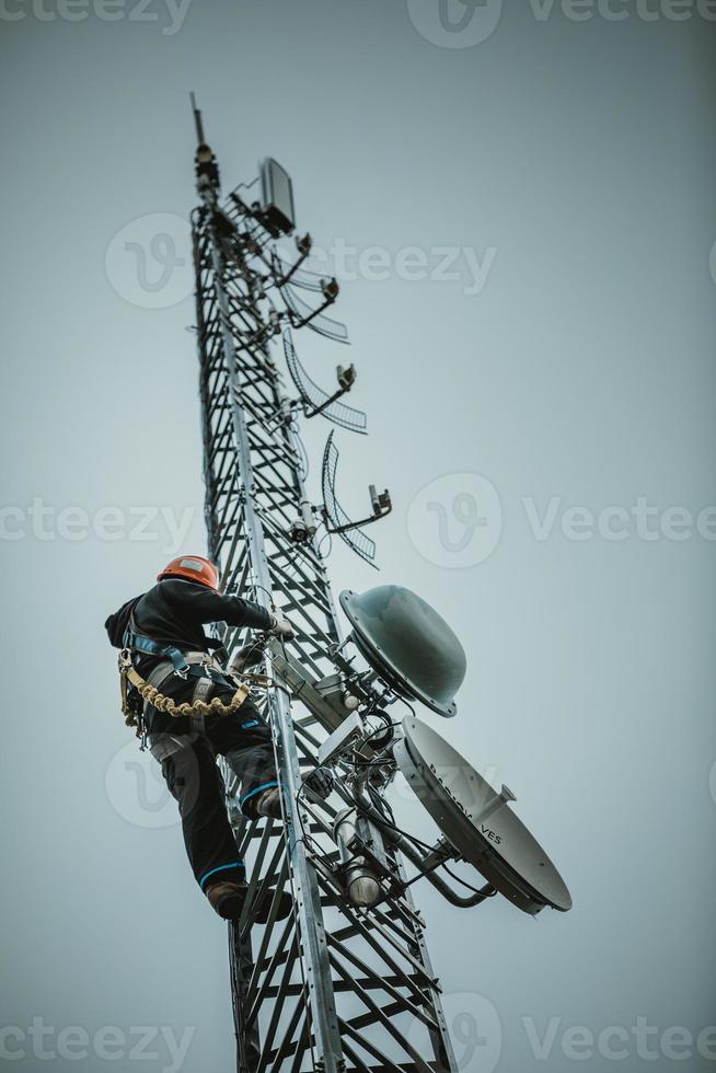 telecommedewerker die antennetoren beklimt foto