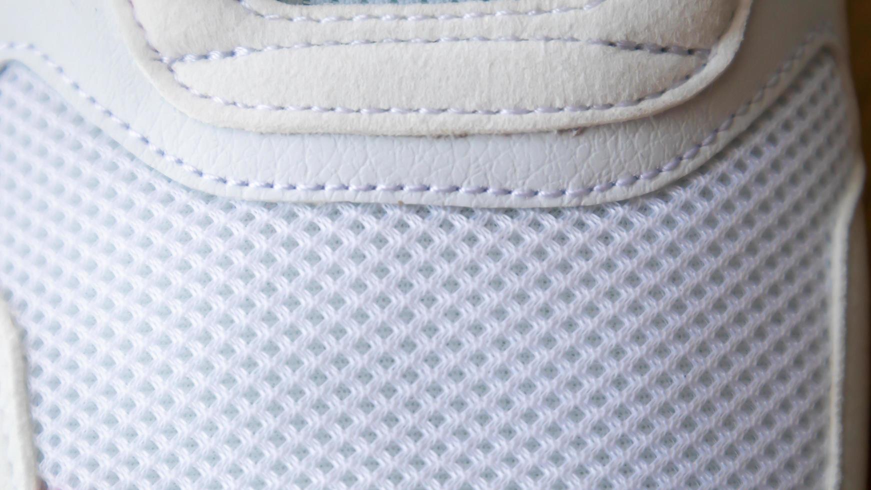 witte kleur mesh stof op een deel van sportschoenen. net voor hardloopschoenen. sportkleding getextureerd rooster. textiel textuur achtergrond. detail van een witte sneaker in stof met veters. fragment van sportschoenen. foto