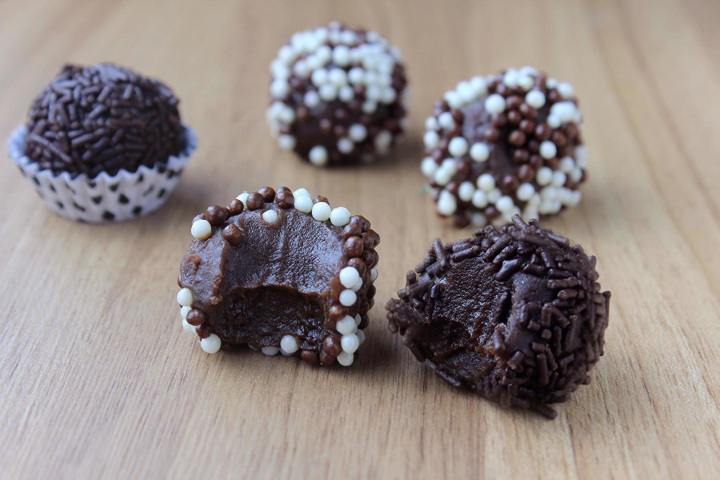 brigadeiro, brigadier, zoete chocolade typisch voor de Braziliaanse keuken bedekt met deeltjes, op een houten achtergrond. foto