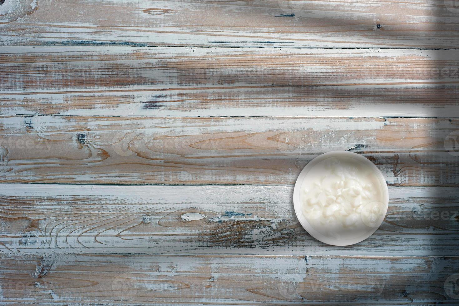 bovenaanzicht van witte botercrème op witte kom over houten tafel. kopieerruimte voor tekst toegevoegd. foto
