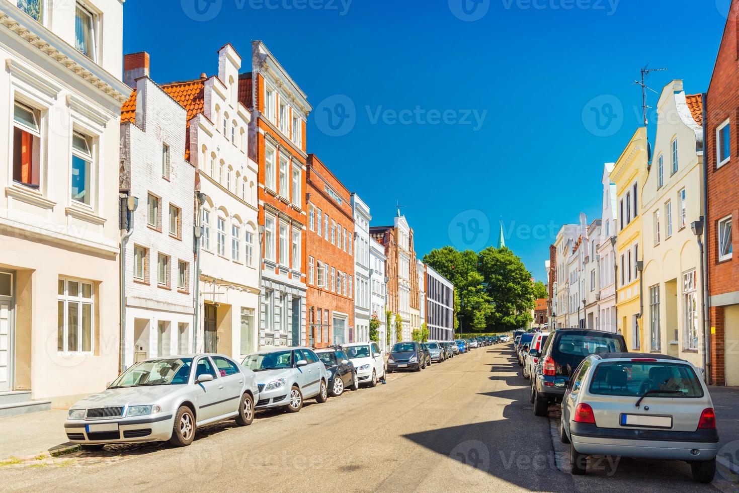 uitzicht op een lege straat in Lübeck, Duitsland. rij woonhuizen en auto's geparkeerd langs de straat foto