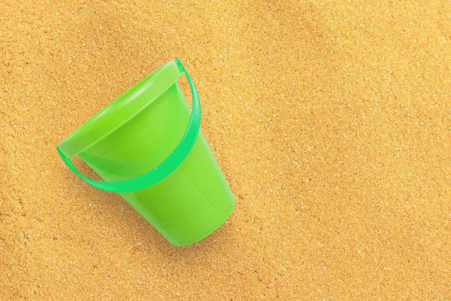 close-up weergave groene zand emmer geïsoleerd op zand strand. kopieerruimte voor tekst toegevoegd. foto