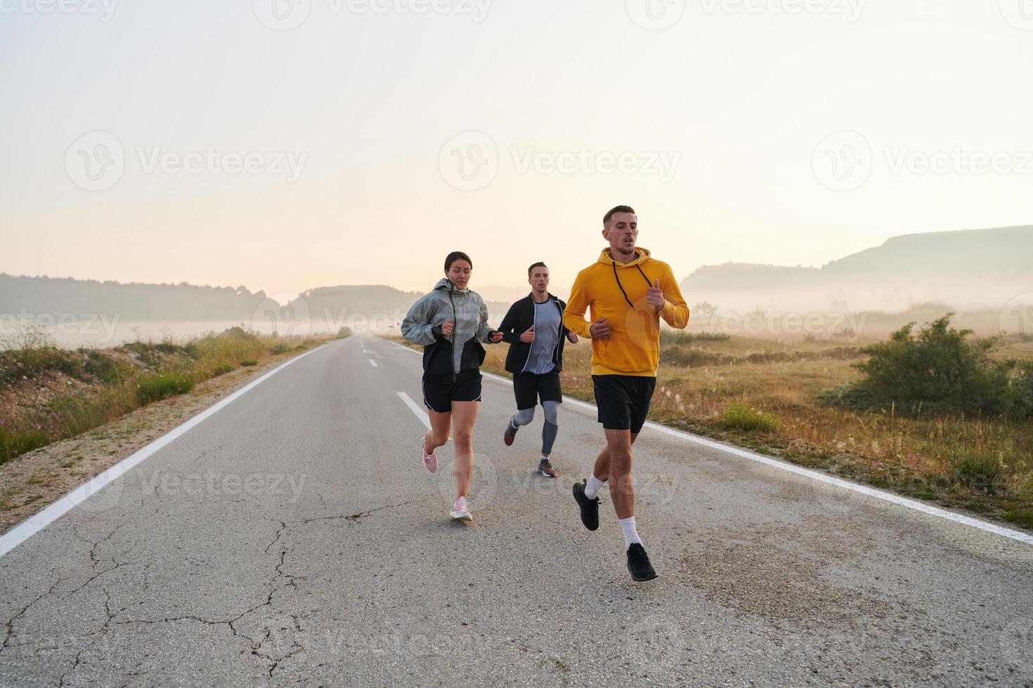 een groep van vrienden, atleten, en joggers omhelzing de vroeg ochtend- uren net zo ze rennen door de nevelig ochtendgloren, bekrachtigd door de stijgende lijn zon en omringd door de rustig schoonheid van natuur foto
