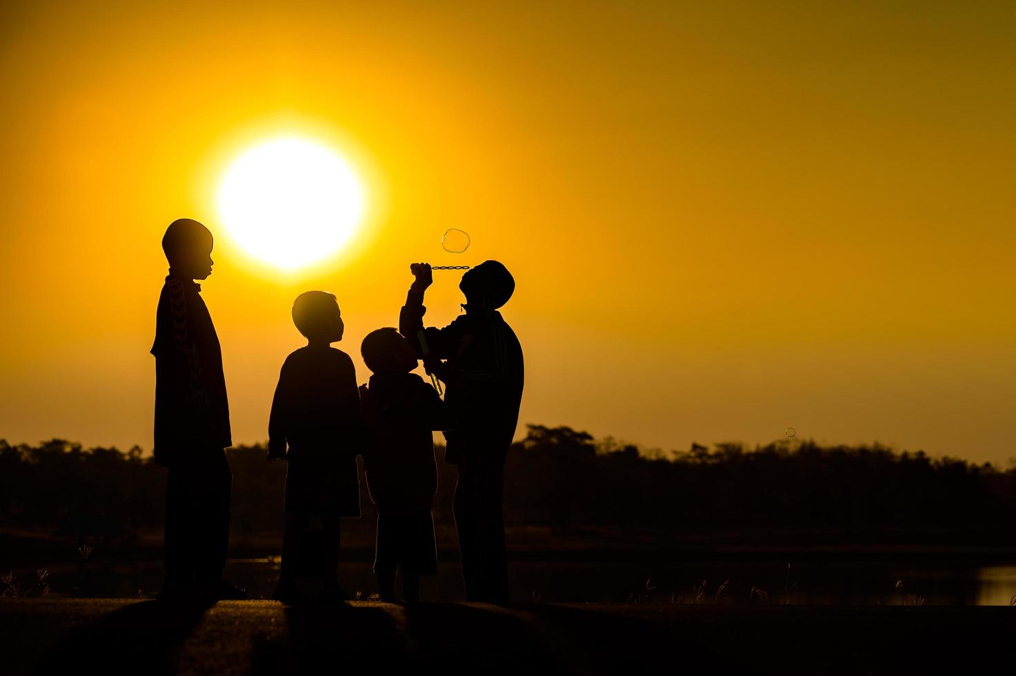 kindsilhouet speelplezier met veel vrienden en spelen tegen de zonsondergang foto