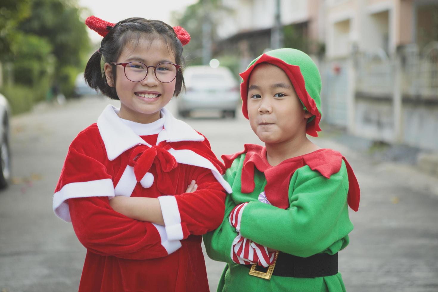 Aziatisch meisje en jongen die het kostuum van de kerstman dragen en buiten spelen met geluk foto