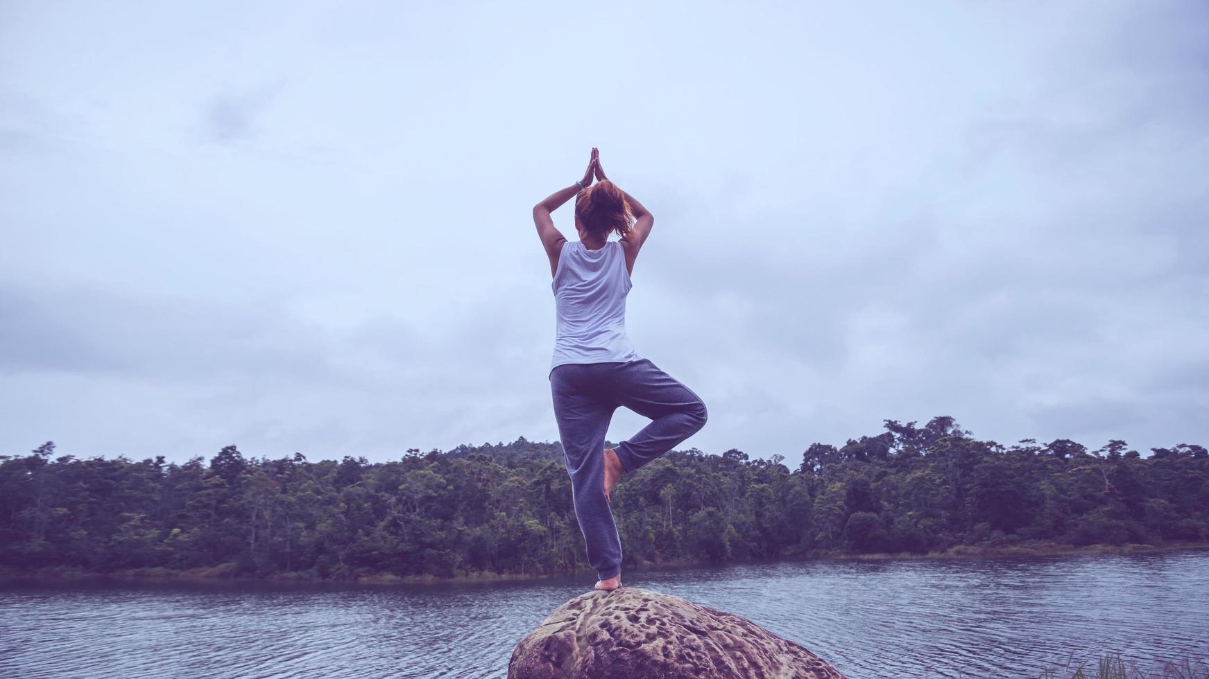 Aziatische vrouwen ontspannen in de vakantie. spelen als yoga. op de rotsen midden in het water. foto