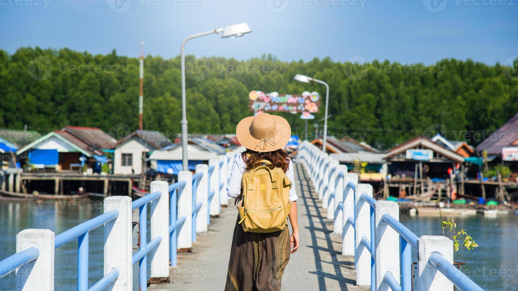 meisje reiziger met rugzak wandelen over de brug over het meer toerisme in landelijke dorpen verbod bang phat - phangnga. aziatische vrouw reizen natuur. reizen ontspannen. reis thailand. zomer, vakantie, toerist. foto