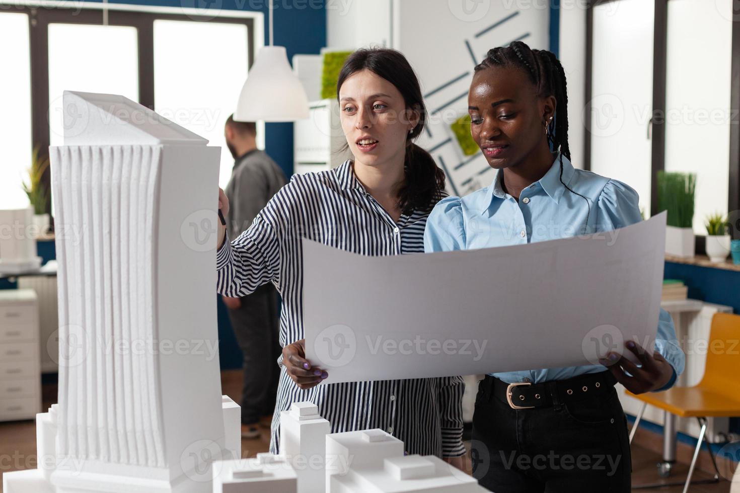 collega's architecten vrouwen controleren plannen van blauwdrukken foto