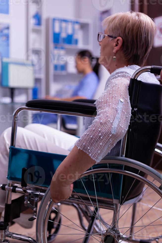 close-up van gehandicapte senior vrouw in rolstoel wachtend op dokter foto