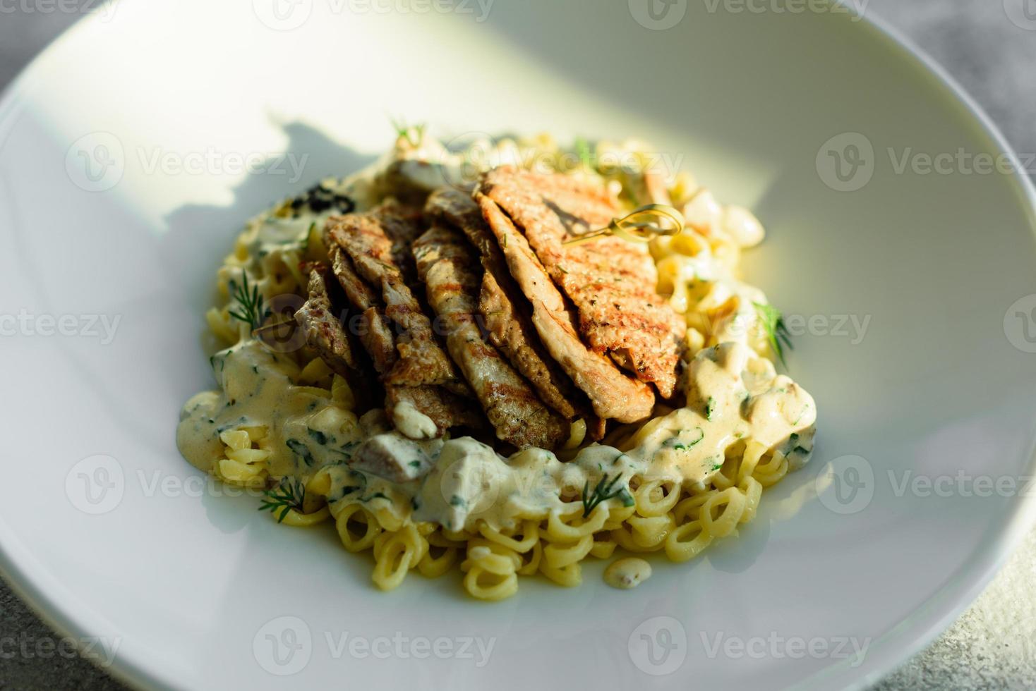 gerecht met stukjes vlees, pasta, greens, saus van een foie gras foto