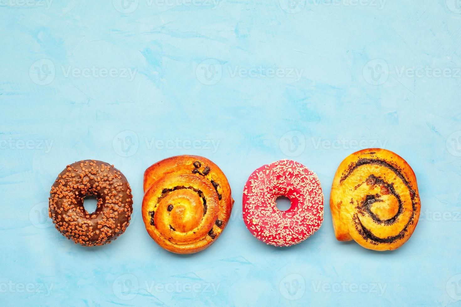 heerlijke chocolade donuts en broodjes met maanzaad en rozijnen op een licht turquoise oppervlak. foto