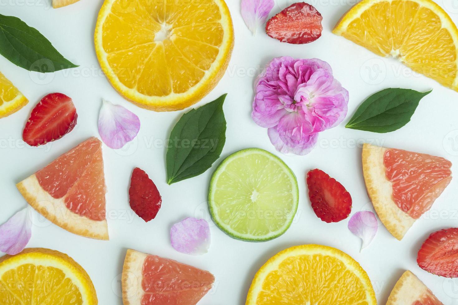 fruit tropische achtergrond. bovenaanzicht, mockup van tropisch fruit op witte achtergrond sinaasappel, grapefruit, limoen, aardbei, thee roze roos en jasmijn bladeren. zomer lichte achtergrond. plat leggen foto