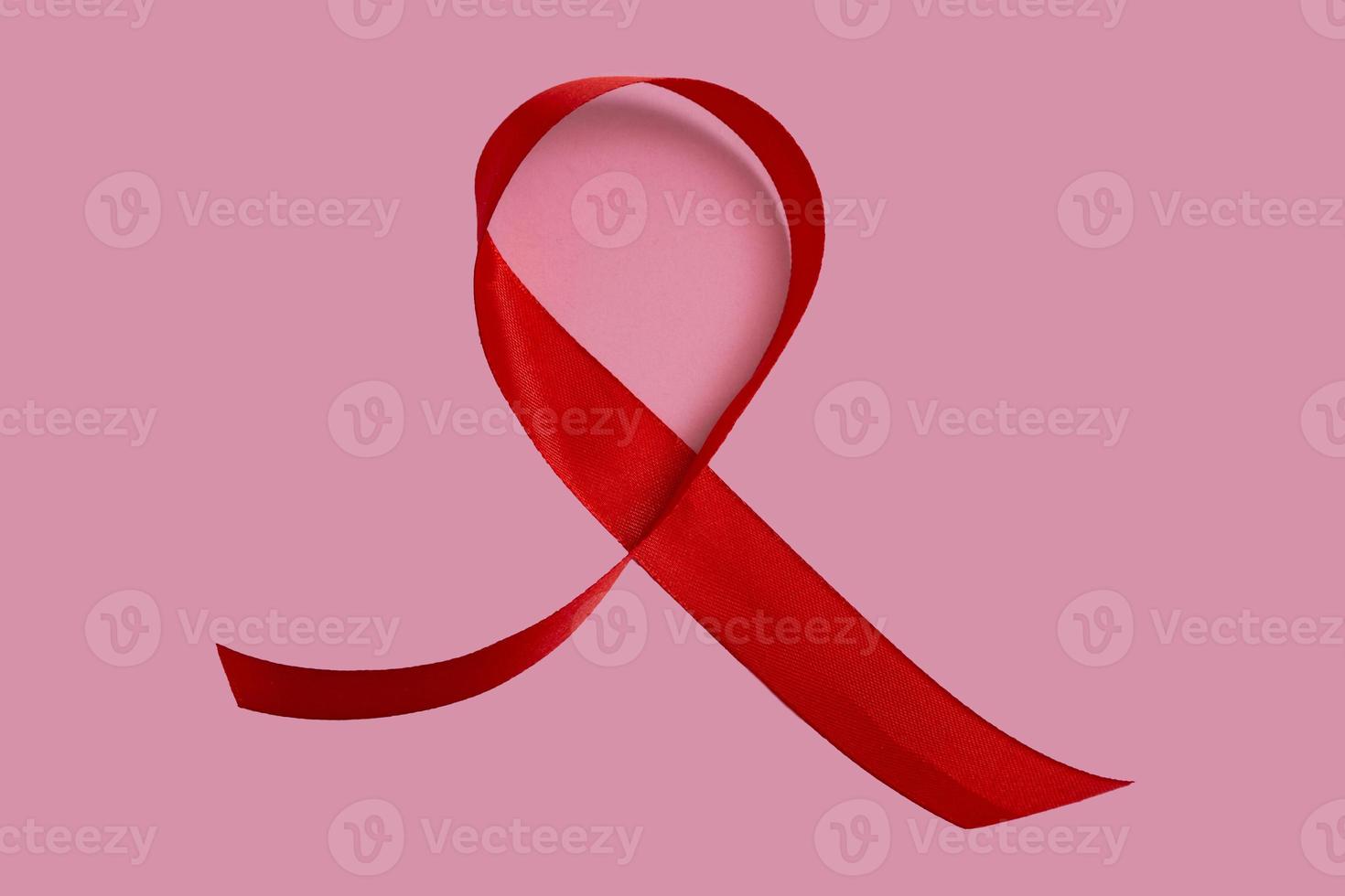 rood aids-bewustzijnslint op roze achtergrond. close-up, kopieer ruimte. foto