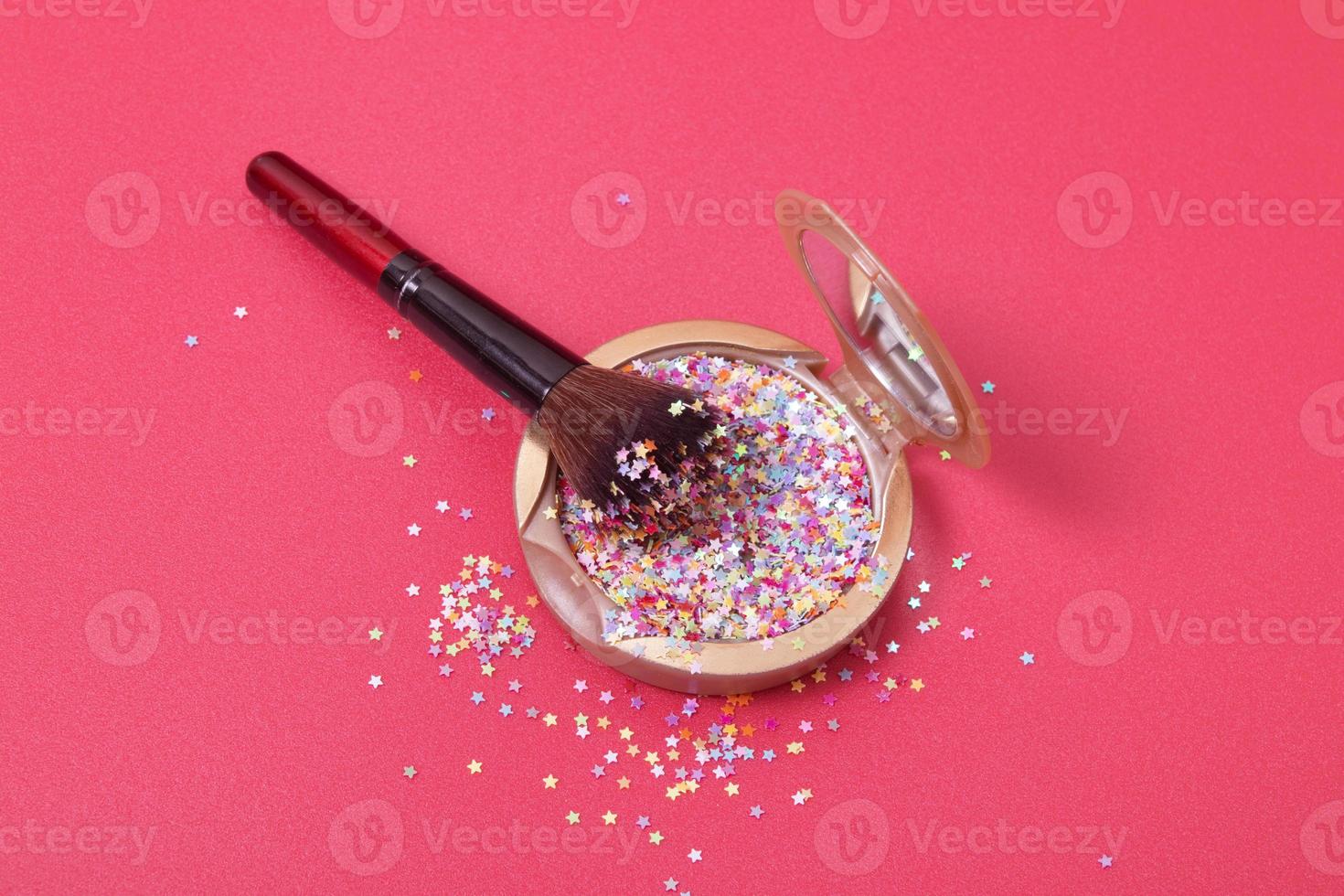 make-uppoeder en cosmetische borstel met glittersterren op rode achtergrond foto