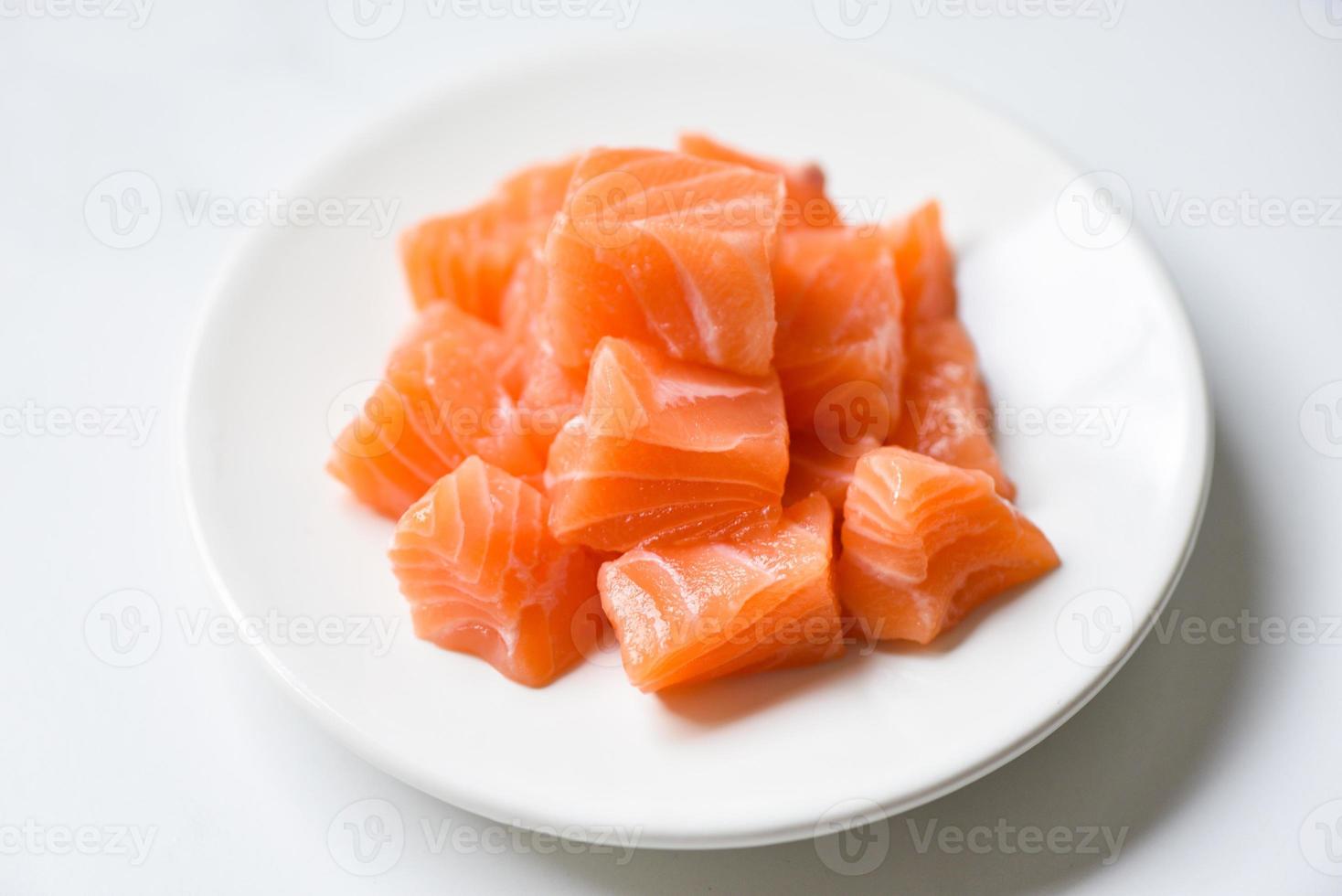 rauwe zalmfilet kubus op witte plaat en witte tafel achtergrond foto