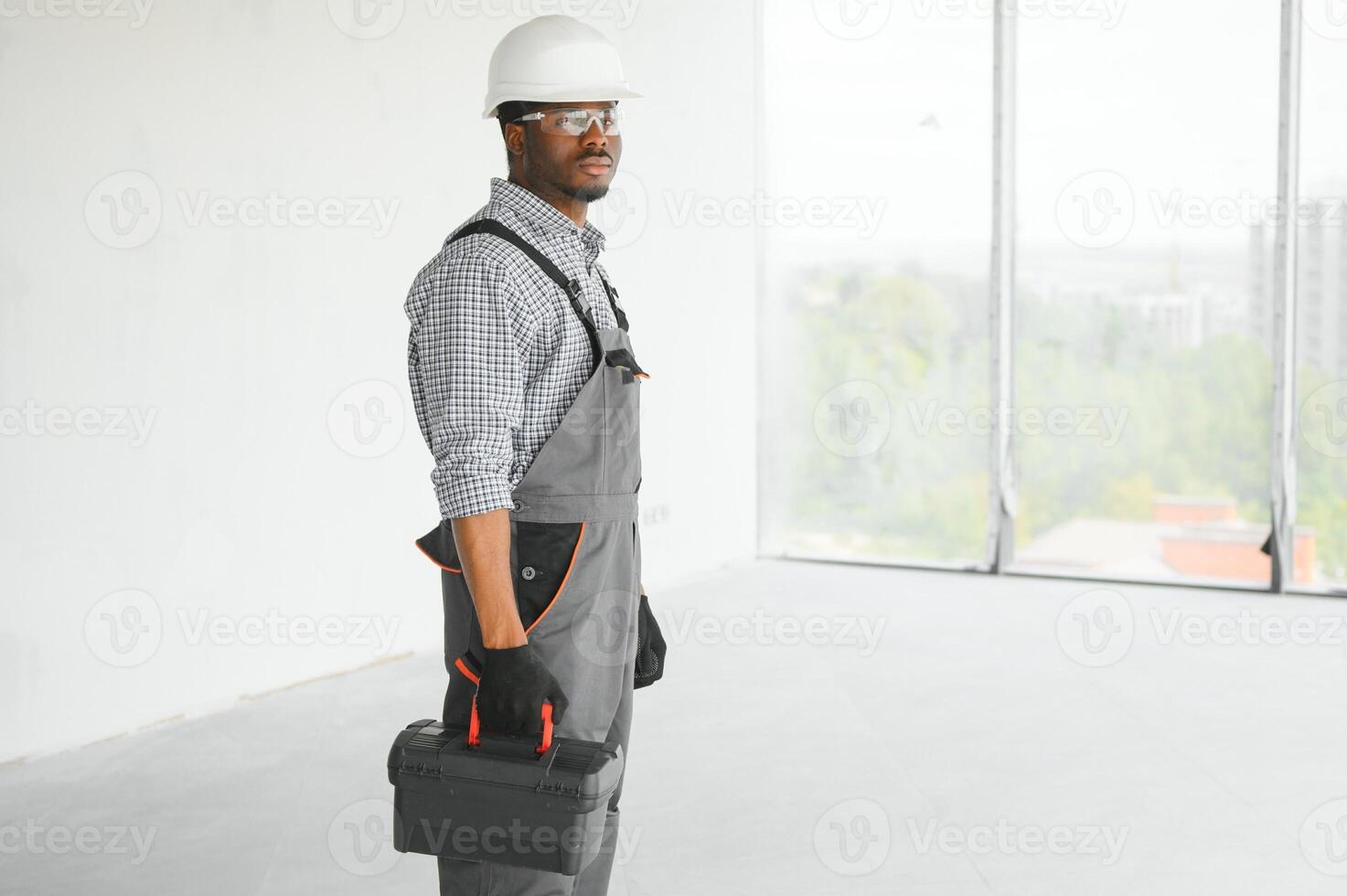 portret van knap jong Afrikaanse Amerikaans mannetje bouwer in moeilijk hoed, werken Bij bouw plaats foto
