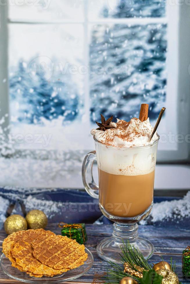 hete koffie latte met kaneelstokjes, bestrooid met kaneel. kerstversiering, takken van een kerstboom. vakantie concept nieuwjaar. foto