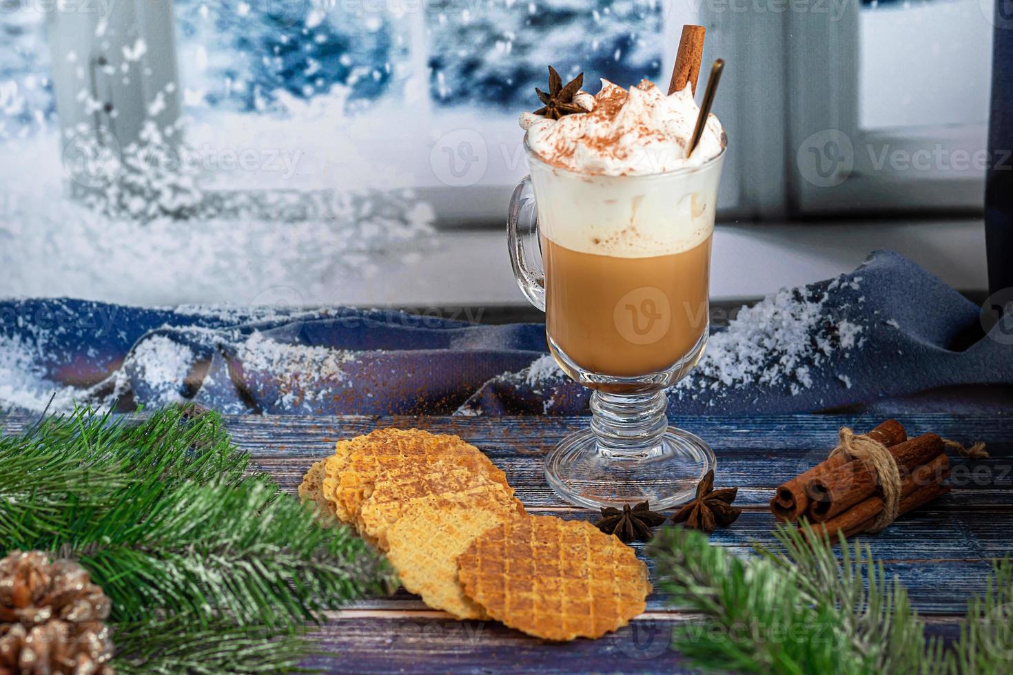 hete koffie latte met kaneelstokjes, bestrooid met kaneel. kerstversiering, takken van een kerstboom. vakantie concept nieuwjaar. foto