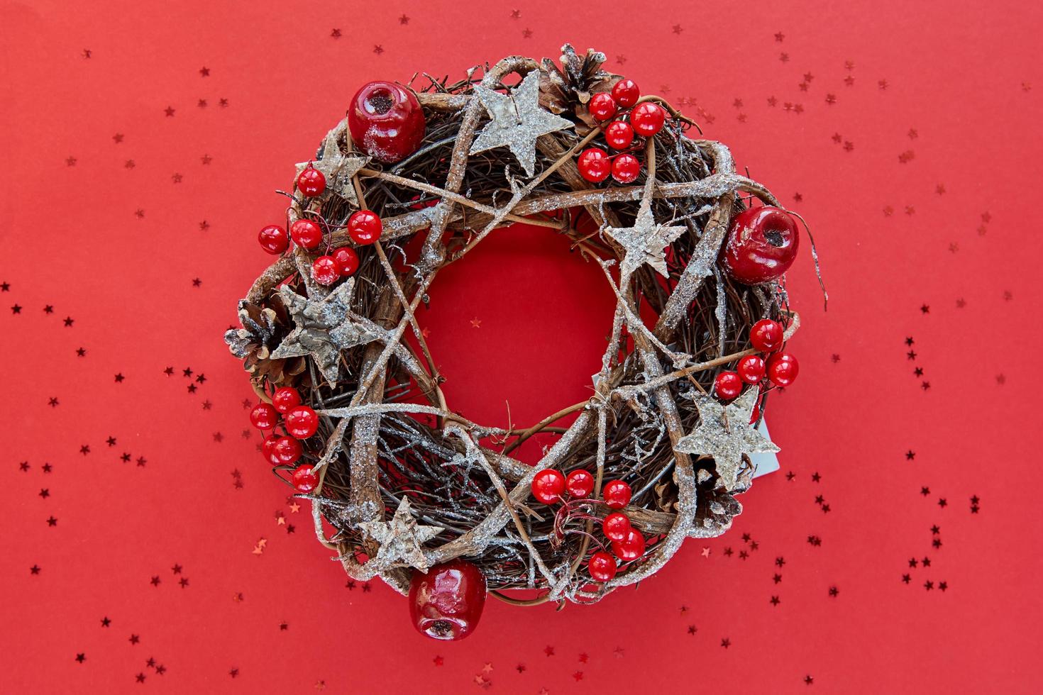 Kerstkrans gemaakt van takken versierd met gouden houten sterren en rode bessen bubbels geïsoleerd op rode achtergrond. creatieve doe-het-zelf hobby. handgemaakte ambachtelijke kerstversiering banner maken foto