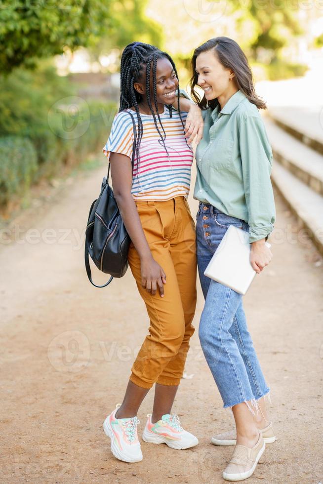 twee multi-etnische meisjes poseren samen met kleurrijke vrijetijdskleding foto