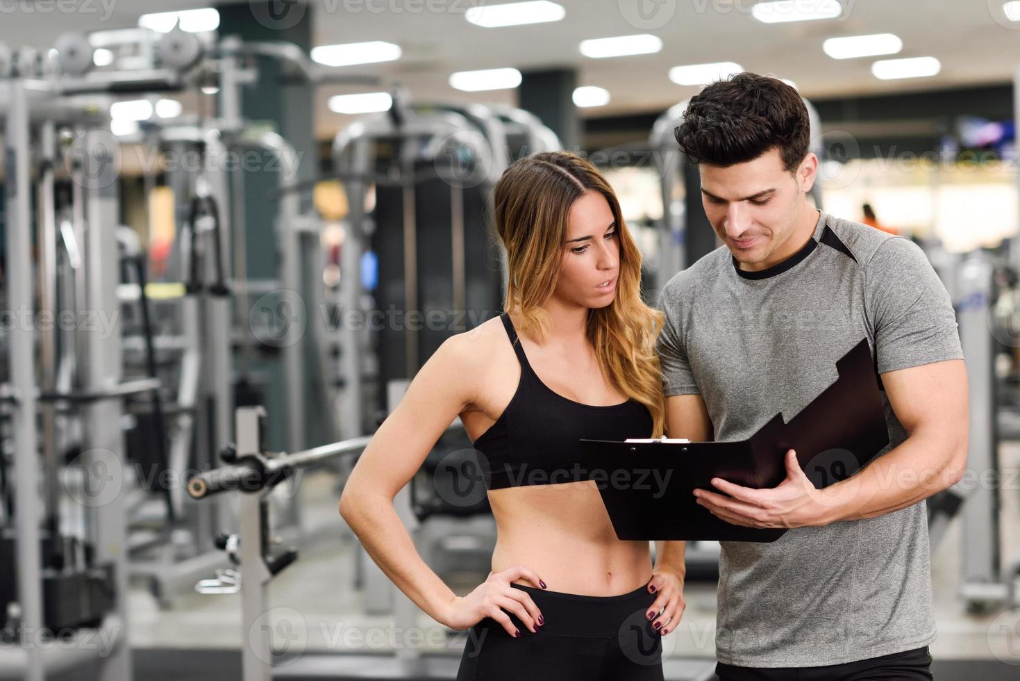 personal trainer en klant kijken naar haar vooruitgang in de sportschool foto