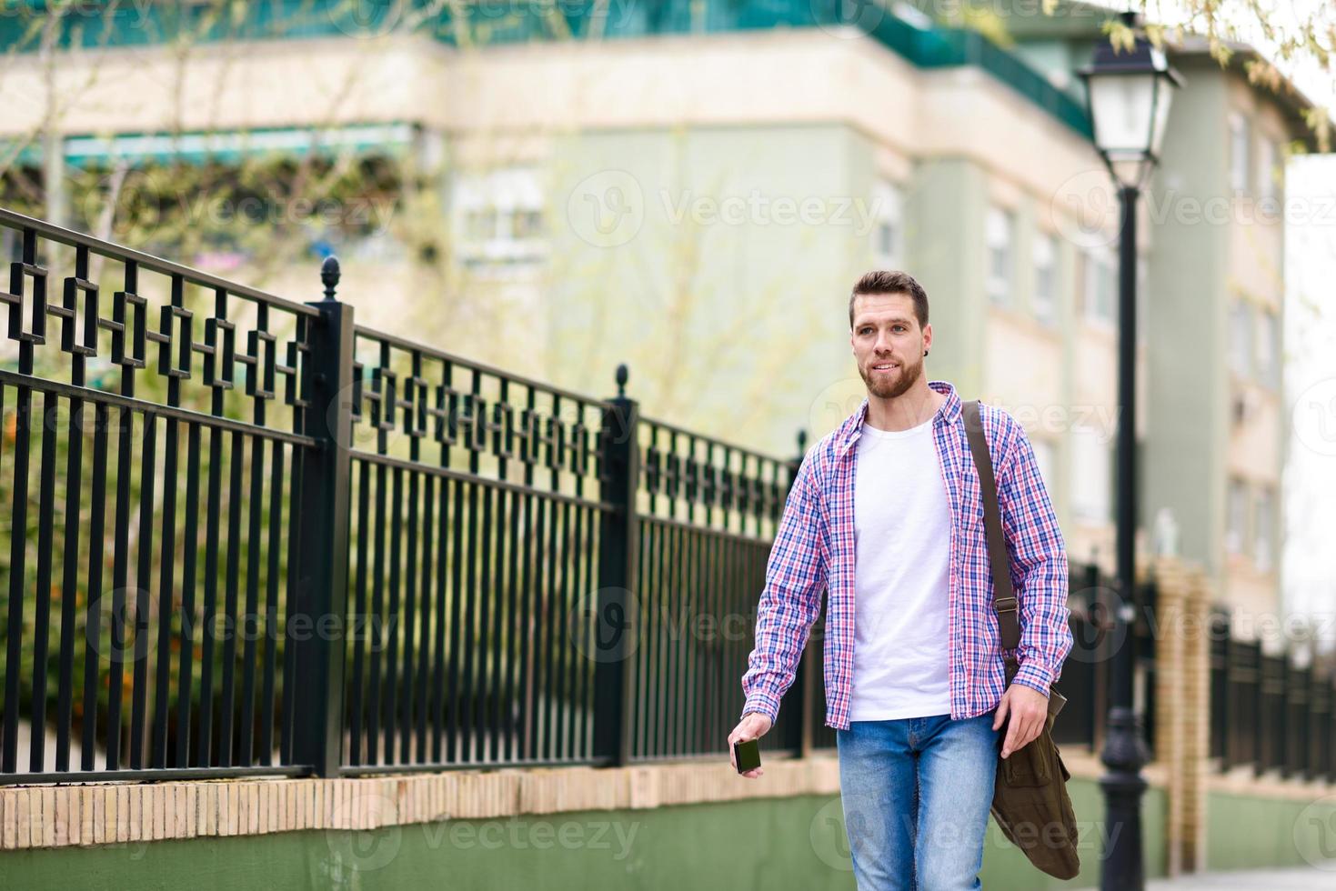 jonge, bebaarde man lopen in stedelijke achtergrond. levensstijl concept. foto