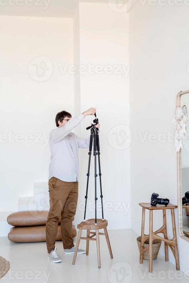 mannelijke fotograaf aan het werk in minimaal licht en luchtig interieur, witte en beige stoel, tapijt en kussens foto