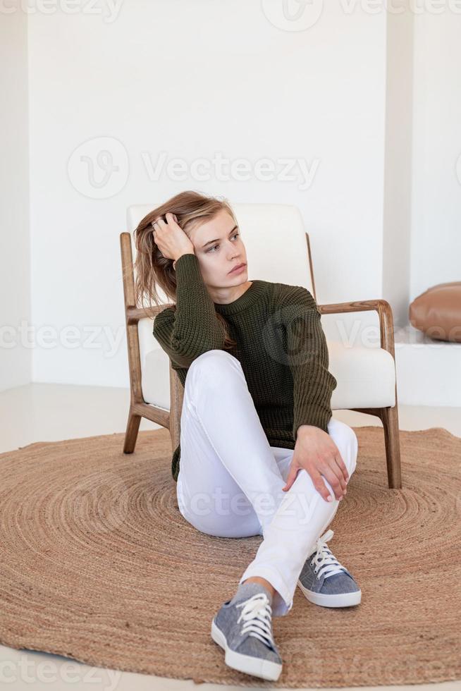 aantrekkelijke jonge vrouw zittend op de stoel in licht en luchtig interieur foto