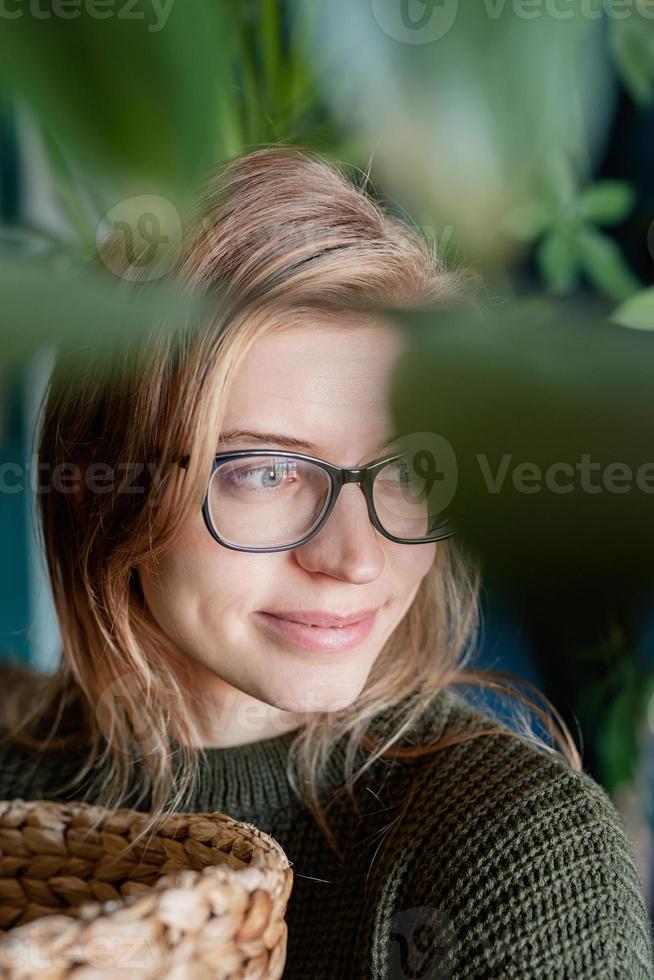 portret van een jonge vrouw die thuis voor de planten zorgt foto