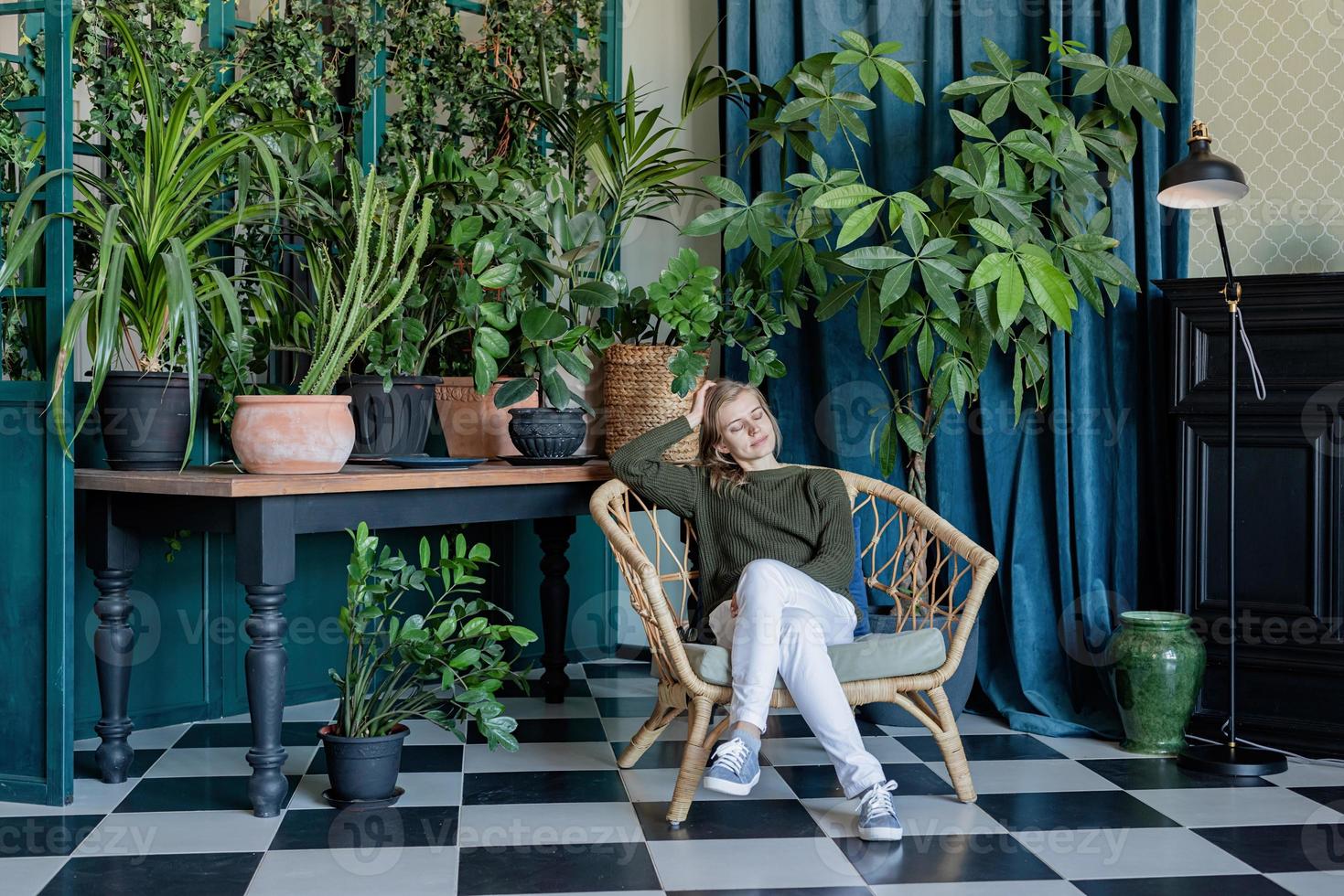 jonge blonde vrouw zittend in een comfortabele stoel omringd met planten foto