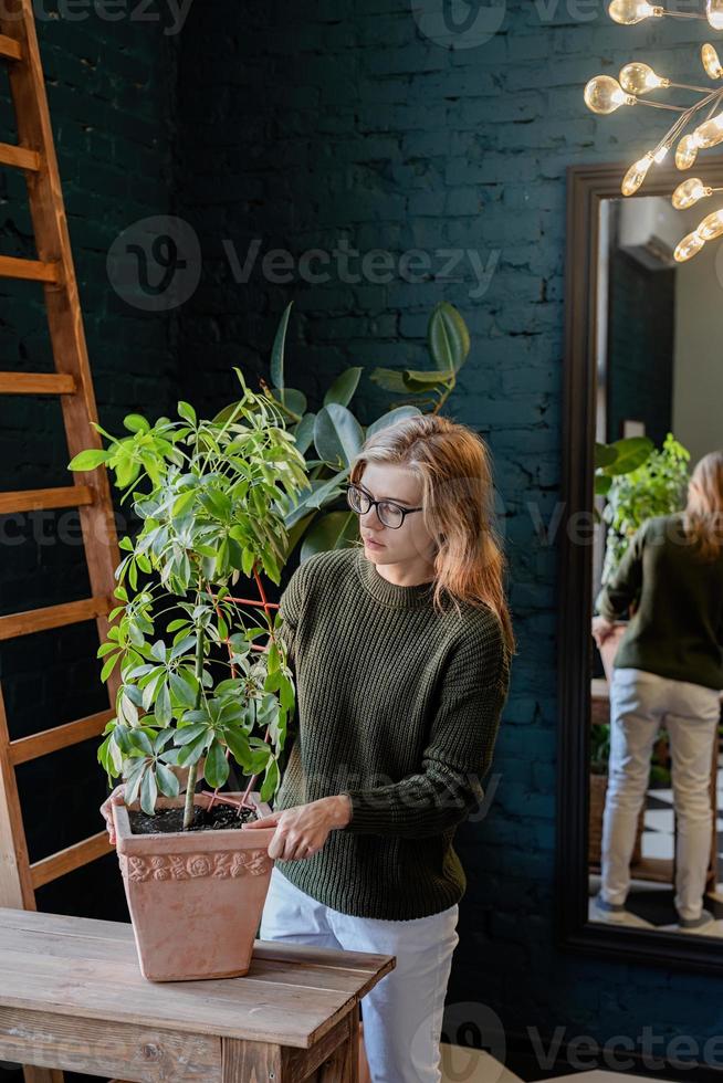 jonge vrouw die thuis voor de planten zorgt foto