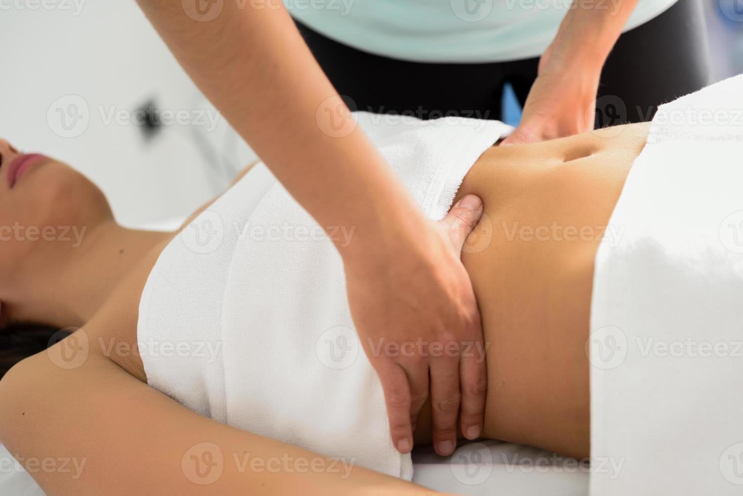 handen die vrouwelijke buik masseren. therapeut die druk uitoefent op de buik. foto
