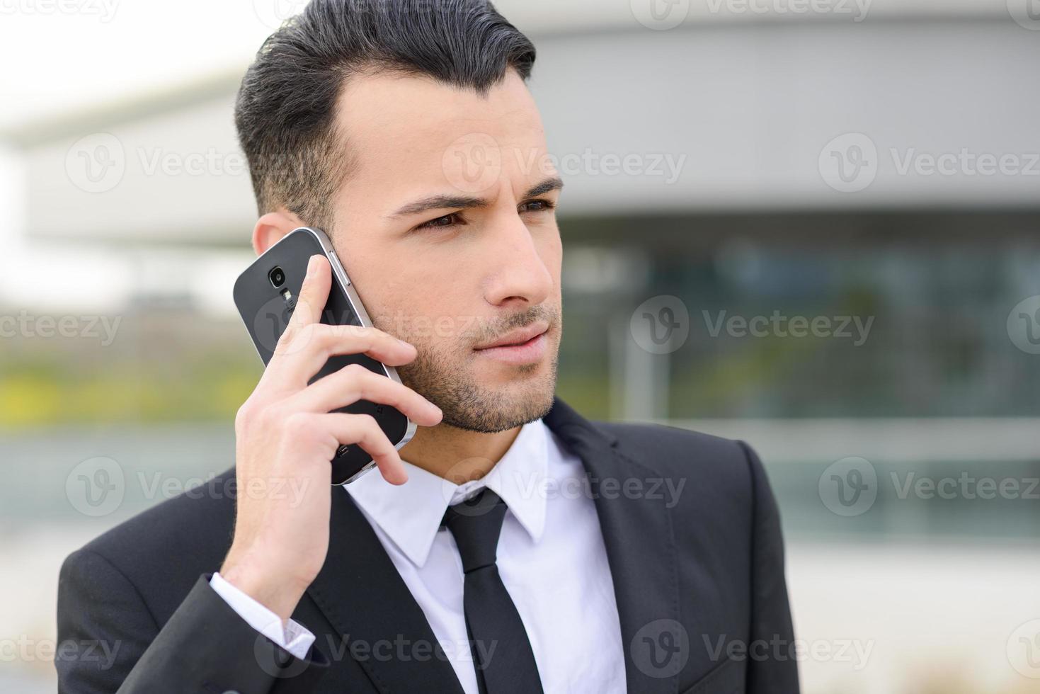 aantrekkelijke jonge zakenman aan de telefoon in een kantoorgebouw foto