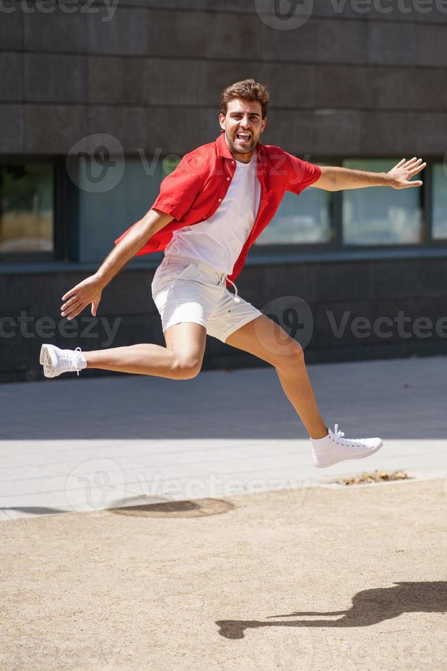 man met vrijetijdskleding die op stedelijke achtergrond springt. foto