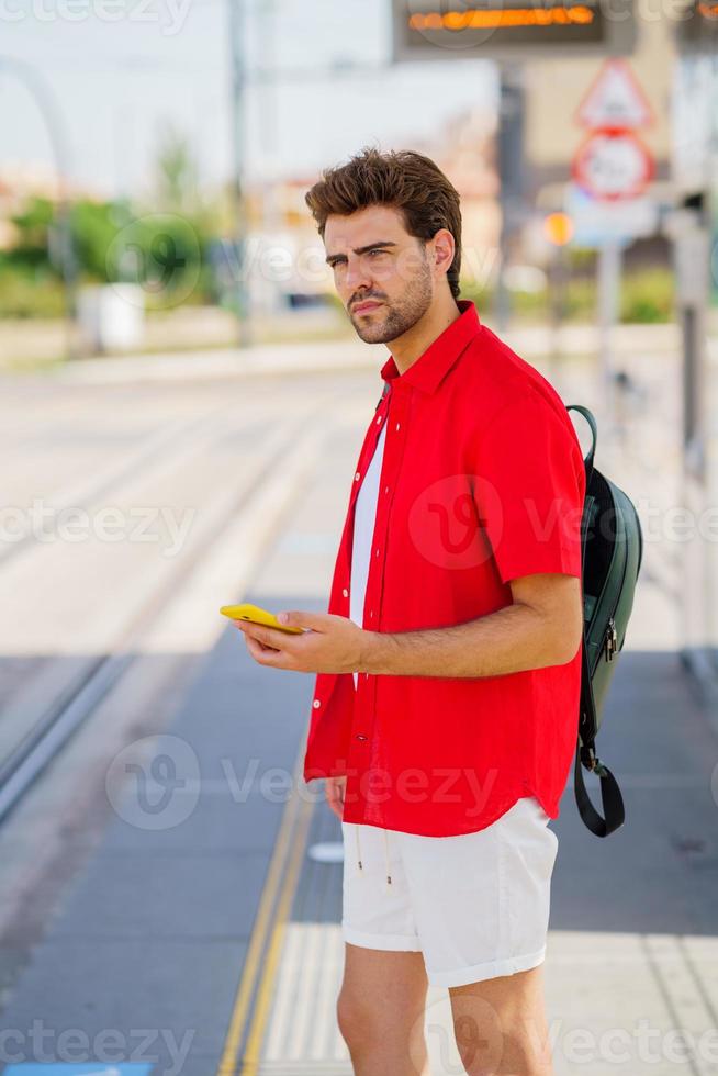 jonge man wacht op een trein op een buitenstation foto