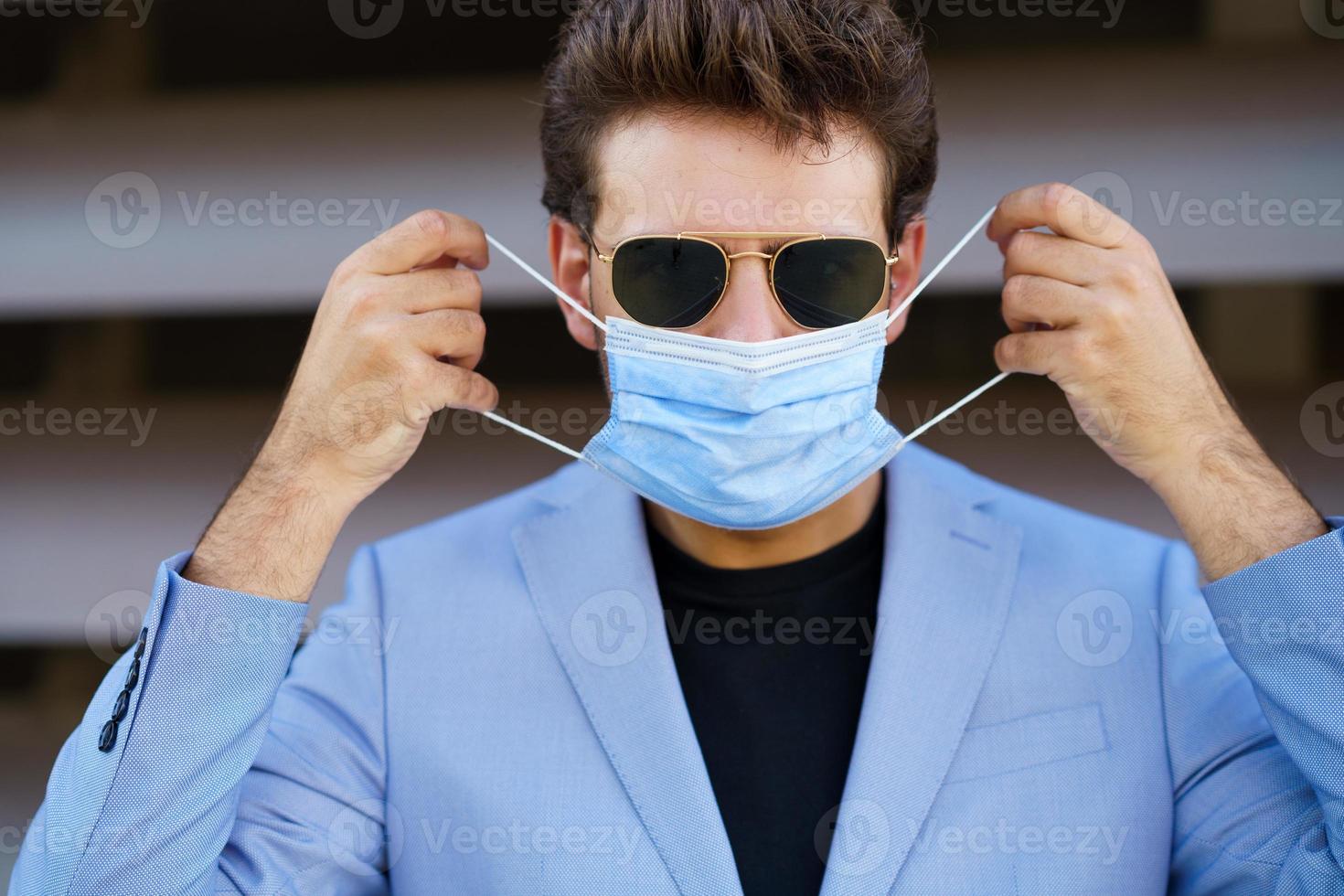 zakenman die een chirurgisch masker opzet ter bescherming tegen het coronavirus. foto