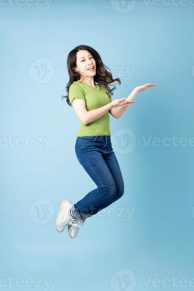 portret van mooi jong Aziatisch meisje dat opspringt, geïsoleerd op blauwe achtergrond foto