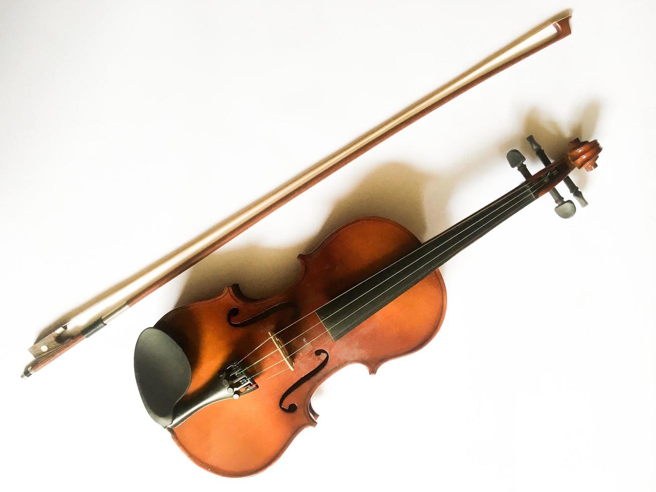 een viool en strijkstok geïsoleerd op wit met kopie ruimte. een klassieke muziekinstrumentaal gespeeld met swiped die meestal wordt uitgevoerd in klassieke muziekshows. foto