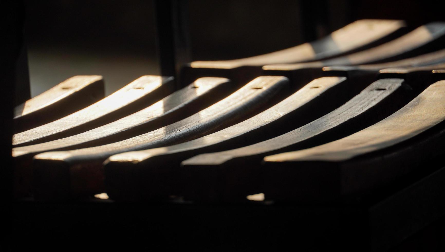 de opstelling van de houten bankmat. zonlicht valt op de houten latten en genereert een abstracte achtergrondstructuur. foto